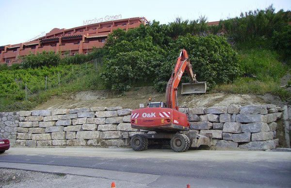 Máquina terminando un muro escollera